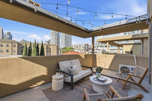 Rooftop deck with lounge seating and string lights over a city skyline